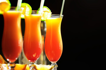 Glasses of Tequila Sunrise cocktail with citrus slices on dark background