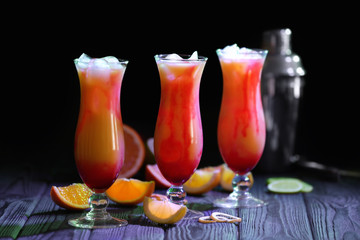 Glasses of Tequila Sunrise cocktail with citrus slices on dark background