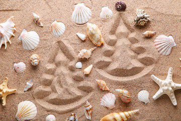 Fototapeta na wymiar Fir-tree drawn on beach sand with seashells