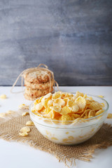 Cornflakes with milk in bowl on wooden table