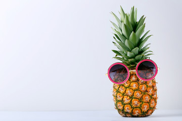 Ripe pineapple with sunglasses on grey background