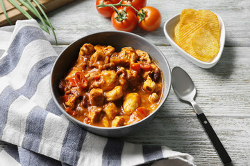 Bowl with delicious chili turkey on wooden table