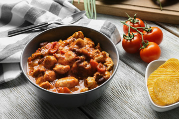 Bowl with delicious chili turkey on wooden table