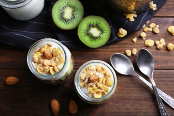 Delicious muesli with kiwi and yogurt on wooden table