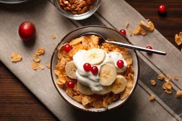 Delicious muesli with banana slices, berries and yogurt on table