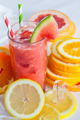 frisch gepresster Saft im Glas mit geschnittenen Zitrusfrüchten und Eiswürfeln garniert