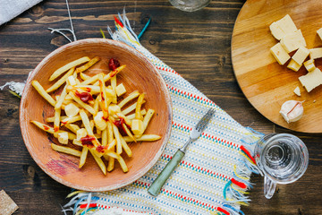 Poutine fries on black surface. Canadian dish with potatoes, cheese and sauce.