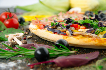 Italian pizza with mozzarella, black olives, prosciutto and tomatoes