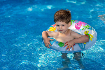 Fototapeta na wymiar young boy playing in swimming pool wirh float ring