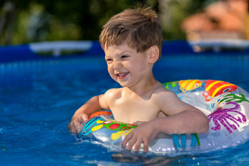 young boy playing in swimming pool wirh float ring