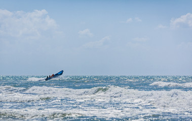 The blue motor boat hurries with rescue team to the aid overcoming big waves of the raging sea.