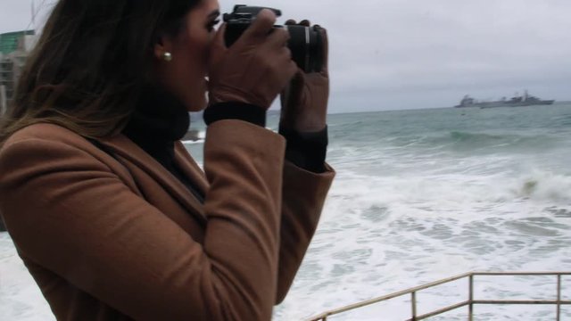 Young adult woman photographer taking pictures and photos of Stormy Sea at Via del Mar, Chile