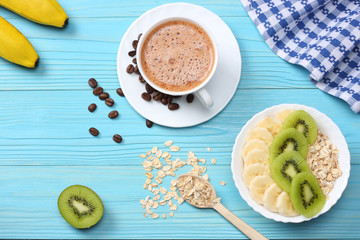 Breakfast with oatmeal porridge, coffee cup and fruits on blue wooden background. Oatmeal with kiwi and banana. Healthy breakfast concept. Top view