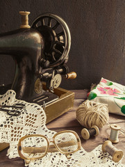 Old antique sewing machine, thread, glasses Concept of manual labor, hobbies and history
