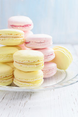 Yellow and pink macaroons on white wooden background.