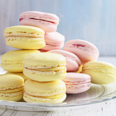 Yellow and pink macaroons on white wooden background.