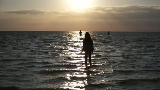 Children go by the sea at sunset