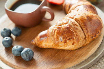 Coffee cup, fresh croissant and berries