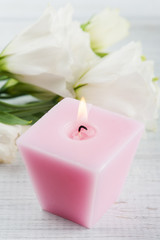 Fototapeta na wymiar Arrangement of white eustoma flowers and pink lit candle
