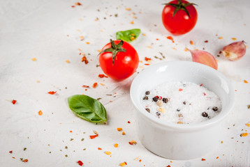 Food background. Ingredients, greens and spices for cooking lunch, lunch. Fresh basil leaves, tomatoes, garlic, onions, salt, pepper. On a white stone table.