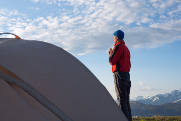 Traveler meets the sun in the mountains and meditates,