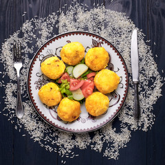 Kubbeh, kubbe, kibbeh - a traditional dish of Iraqi cuisine. Delicious rice balls with meat filling and vegetable salad. Rice seeds are scattered on a wooden table. 