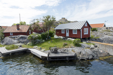 Fototapeta na wymiar Some red Swedish houses on an island with water inf front of the houses