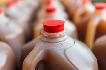 Rows of plastic gallon jars on display filled with apple cider
