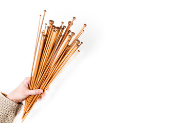 Brown wooden knitting needles in woman hand on white background. Top view