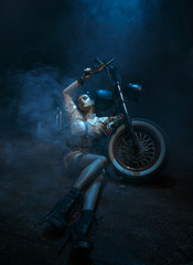 Beautiful, sexy near the bike. Clothes in the steampunk style. Dark background with smoke. Creative colors.