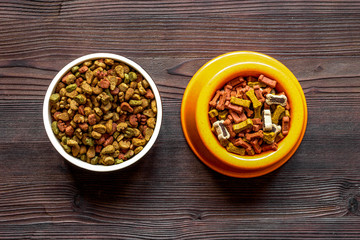 dry dog food in bowl on wooden background top view