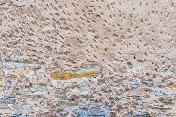 Stone wall background texture with old, rusty, and peeling rocks and yellow and blue colors