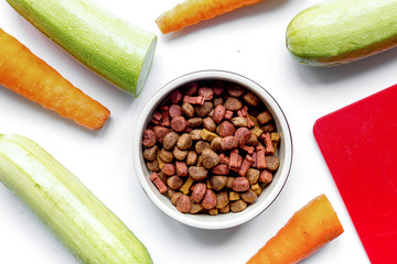 Dry dogfood with carrot and zucchini on table background top vie