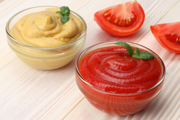 mustard ketchup in glass bowl on white wooden background.