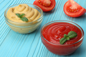 mustard ketchup in glass bowl on blue wooden background.