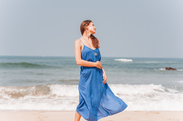 beautiful girl standing near by the sea in blue dress
