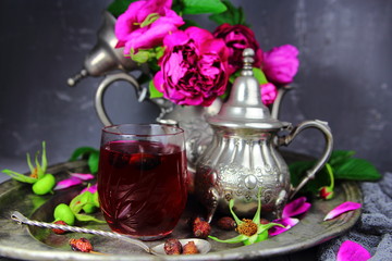 Obraz na płótnie Canvas чай из шиповника на серебряном блюде с букетом цветов