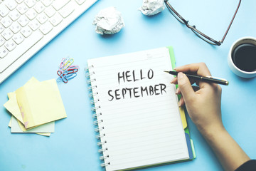 woman written hello september text on notepad