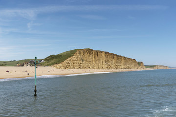 The beach and golden strata of the East Cliff at West Bay on the Jurassic coast in West Dorset...