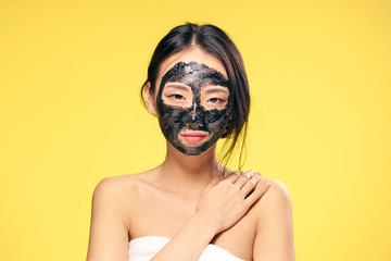 Woman in a cosmetic mask, facial, woman on a yellow background