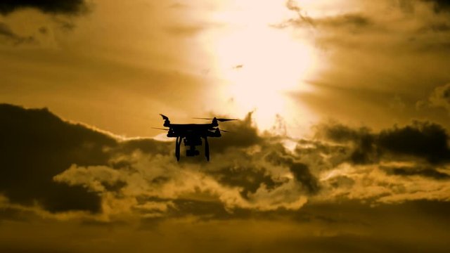 Drone silhouette flying in sunset landscape