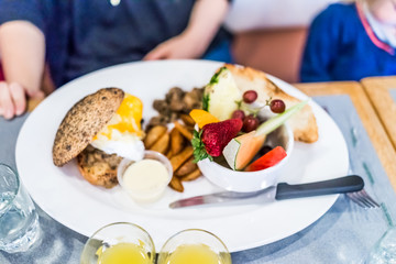 Brunch plate in restaurant with fruit, eggs, toast, potatoes and poached egg