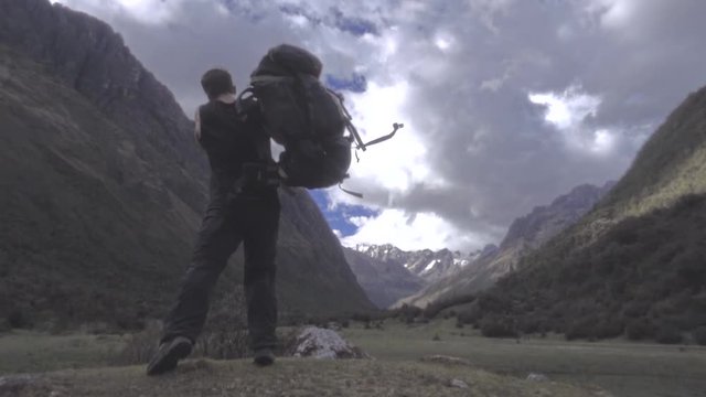Hiker carries his backpack on top of rocky mountain, Huascaran Park, Peru. Slow motion	
