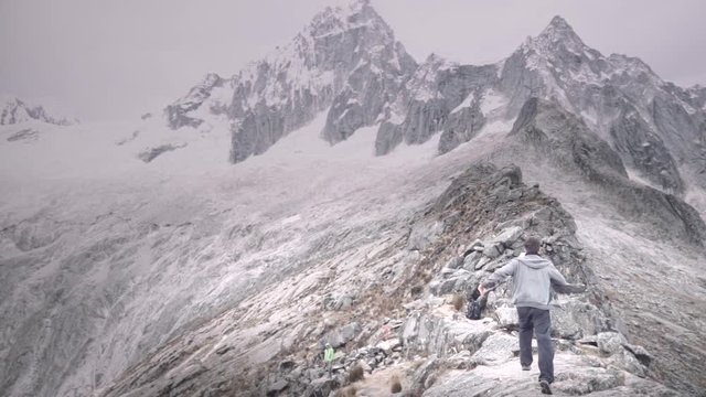 Causacian male runs of happiness on top of rocky mountain, Huascaran Park, Peru. Slow motion	