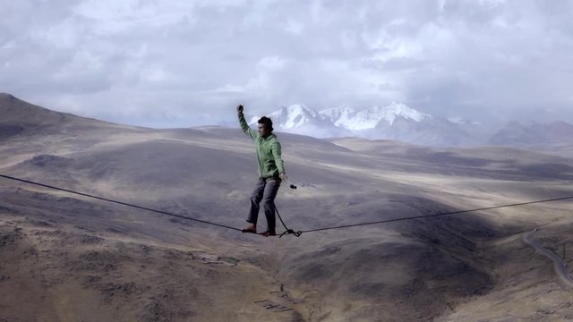 Slackliner balancing on tightrope between two rocks, Snowy mountains of the Huascaran park on the background, Peru. Slow motion	