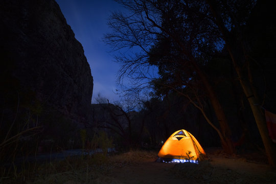 Camper with light on in tent under night sky Grand Canyon Arizona
