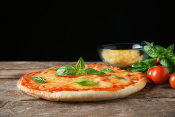 Tasty pizza with basil leaves on wooden table