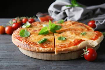 Tasty sliced pizza with basil leaves, closeup