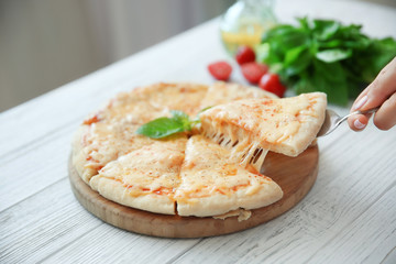 Tasty sliced pizza with basil leaves on wooden table