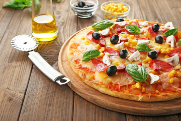 Plate with tasty pizza, its ingredients and knife on wooden table